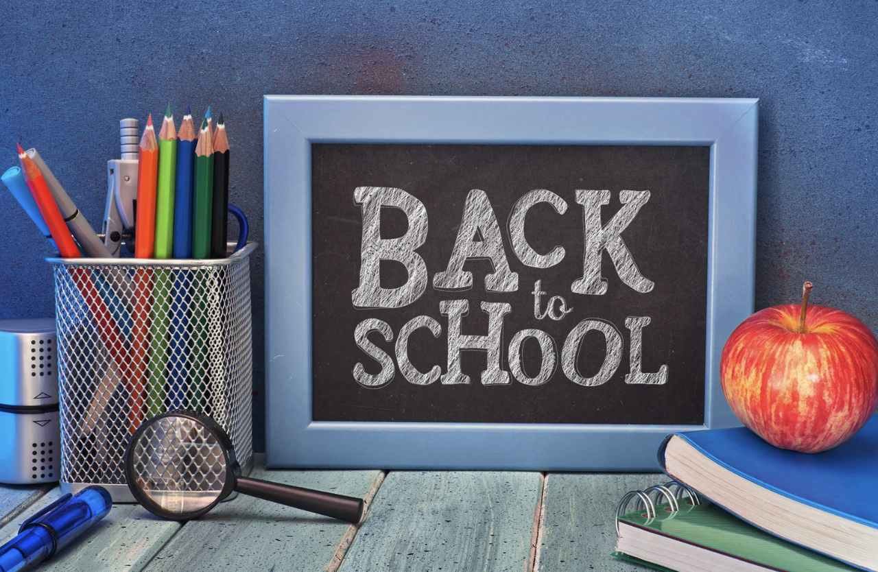 Image of school supplies on a table with a small chalkboard that reads "Back to School"