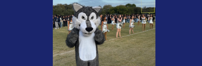 Cody the Coyote cheering with students during a pep rally