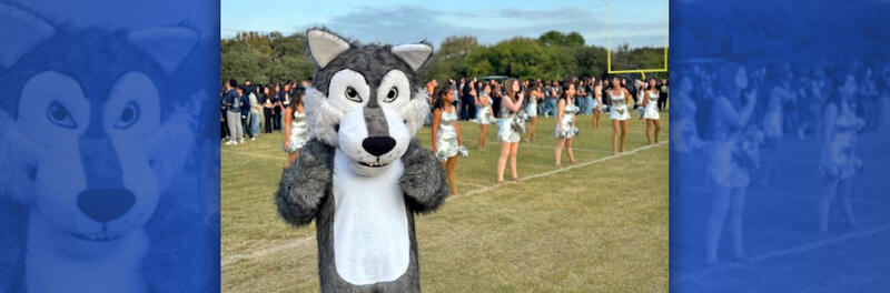 Cody the Coyote cheering with students during a pep rally