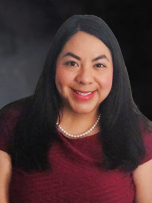 Ms. Wade wearing a burgundy top and pearls.